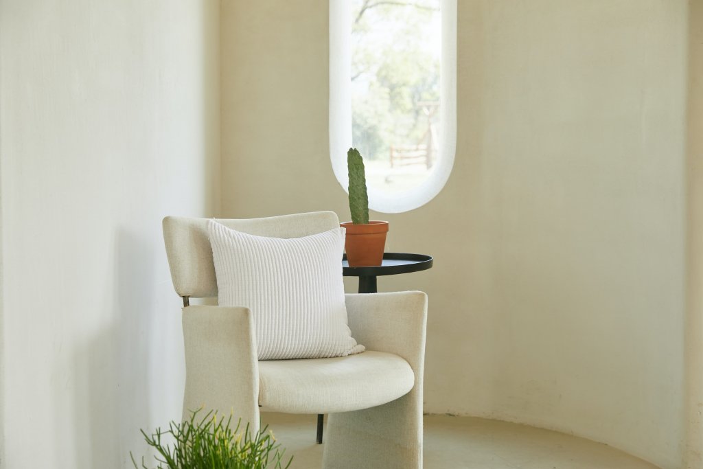 cuarto blanco con con silla color crema y cactus