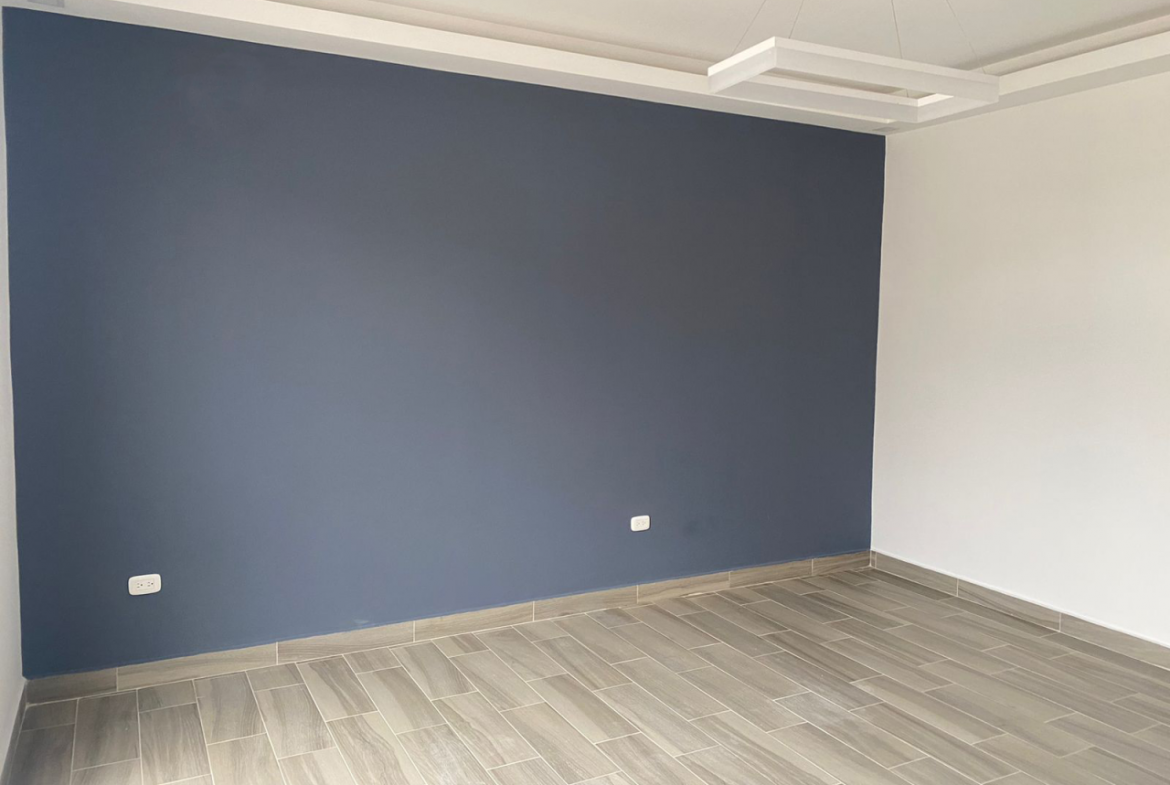 Habitación con acabados modernos color blanco, una pared color azul, y el piso de porcelanato tipo madera.