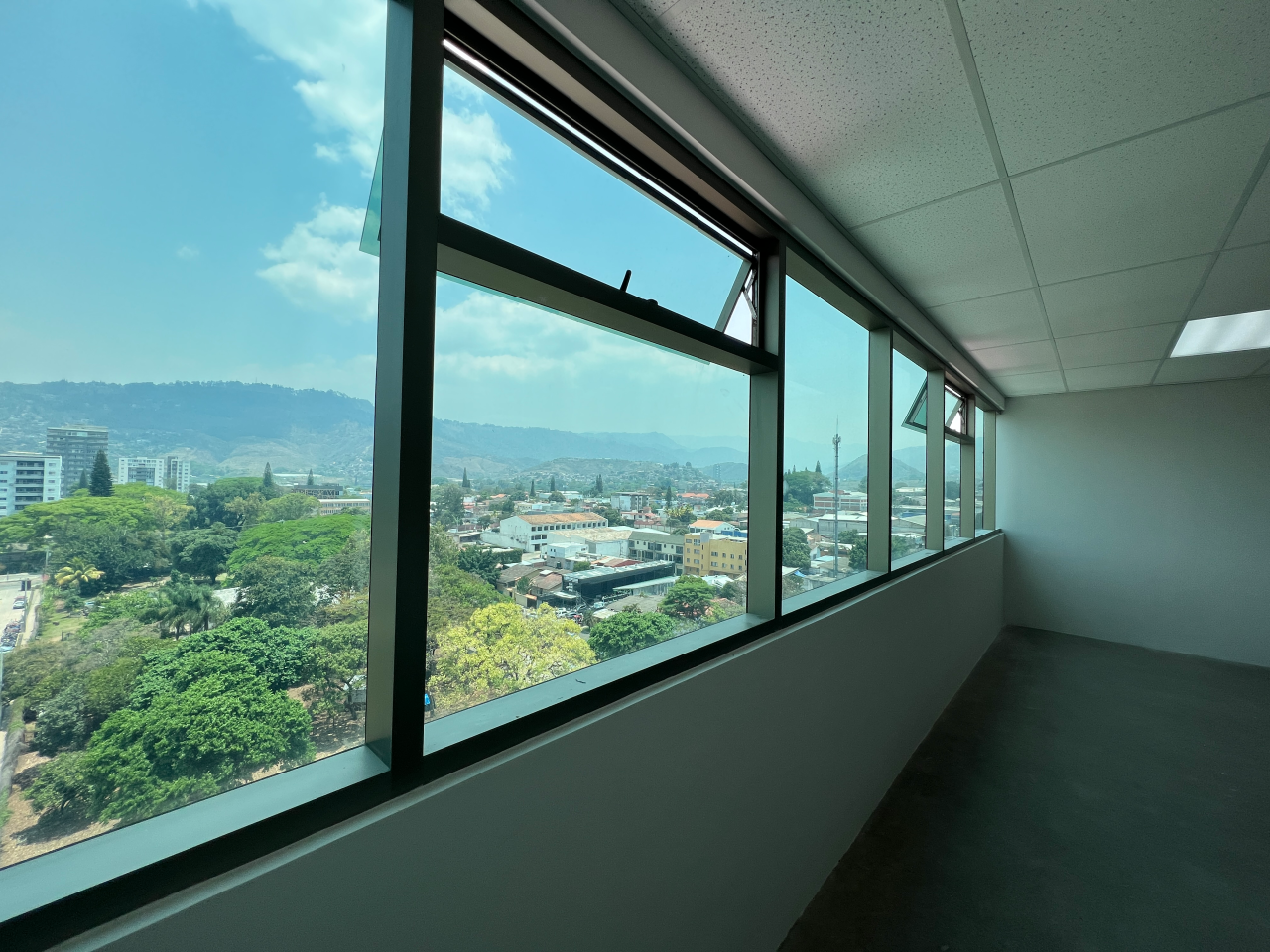 Ventana de vidrio larga horizontal con vista de día a la ciudad de Tegucigalpa en oficina torre Agalta