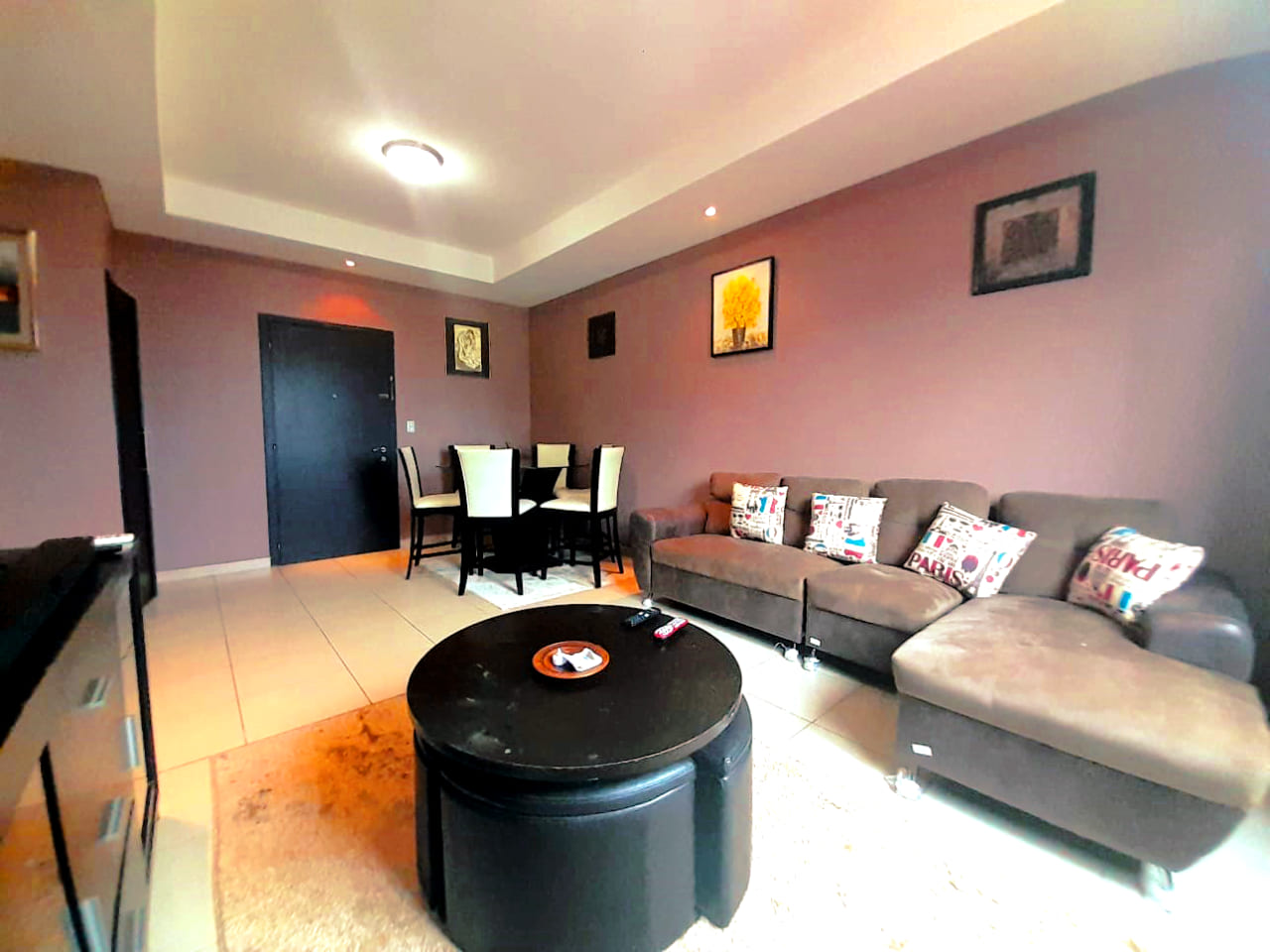 Amplia sala amueblada con sofas color cafe mas muebles de color negro.