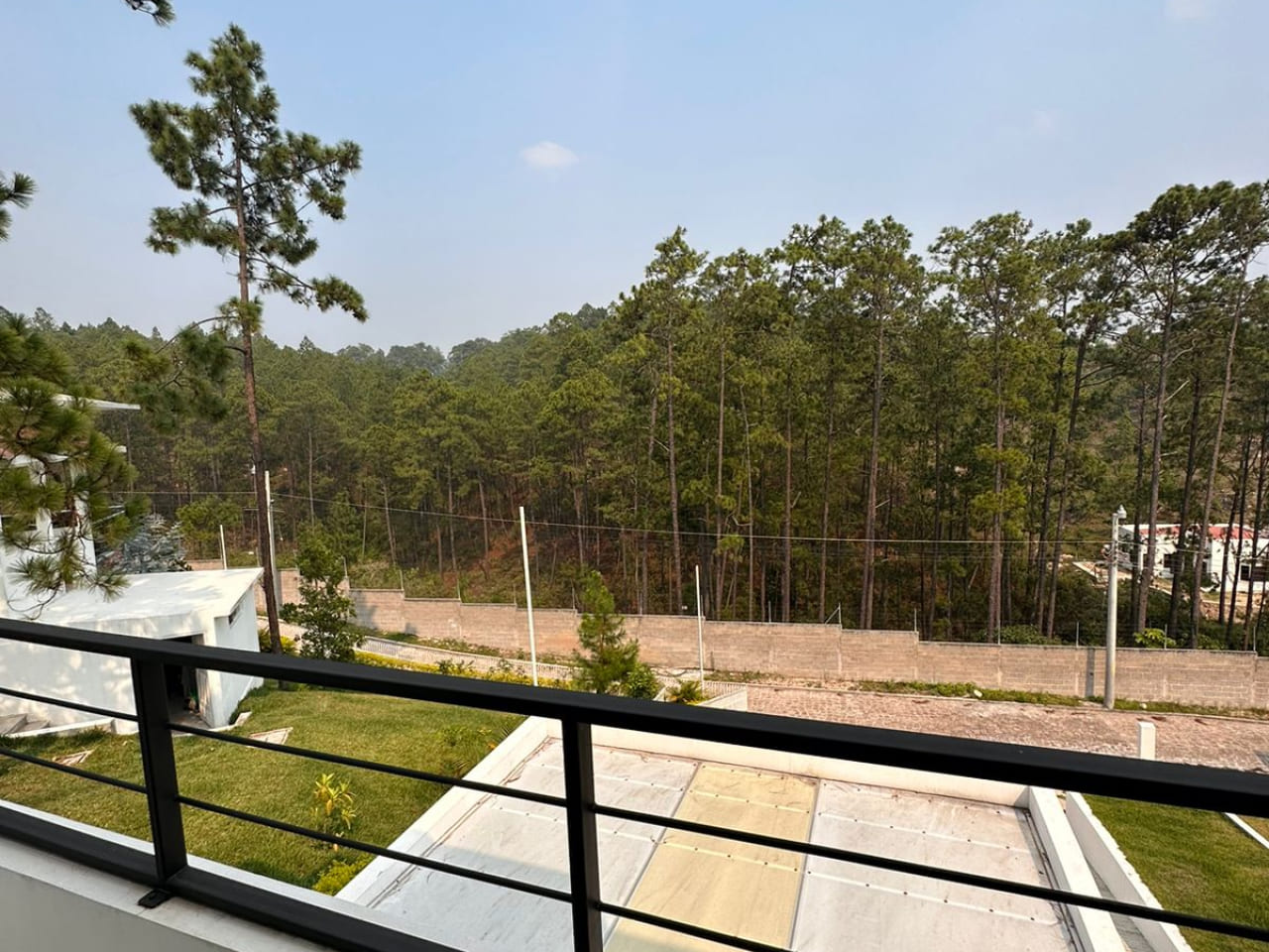 Fotografía donde se puede apreciar la vista desde el balcón, que da hacia el exterior de la propiedad y cuenta con un bello paisaje de una arboleda de pinos.