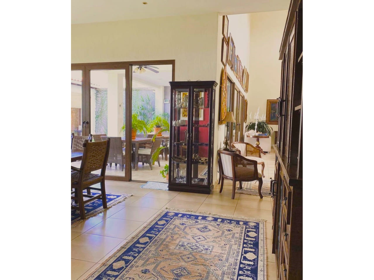 Pasillos de la casa en venta , con alfombla de color azul, mueble de madera con adornos de ceramica, junto al pasillo de la sala de estar y a la puerta del patio trasero.