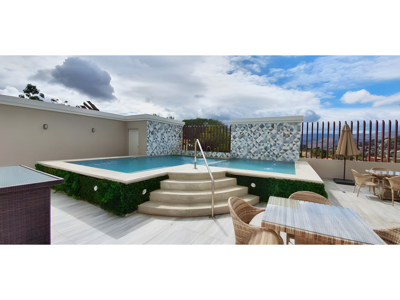 El área de piscina cuenta con mesas en la terraza, un área de piscina con bella agua azul y una impresionante vista de la ciudad.
