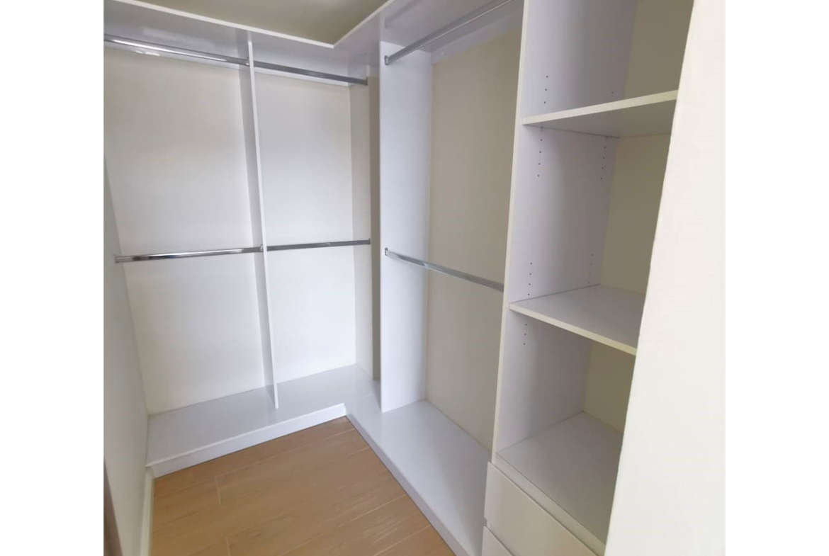 Walk-in closet con paredes de color blanco y divisiones de color blanca a juego, perfecta para guardar y colgar toda la ropa que necesites.