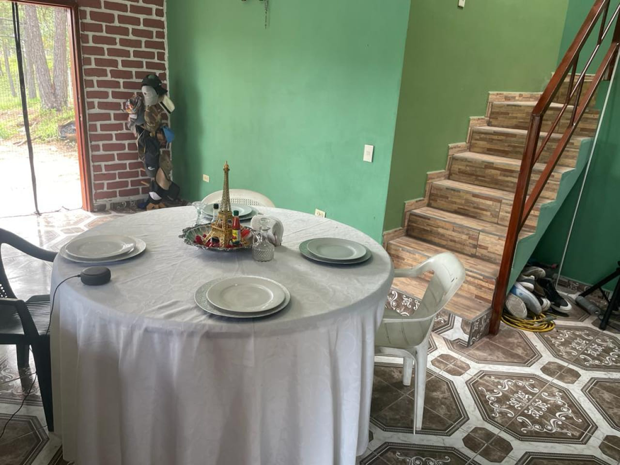 Sala de comedor con pared color verde, piso de cerámica, escaleras con acceso al 2 nivel y una puerta corrediza al patio trasero.