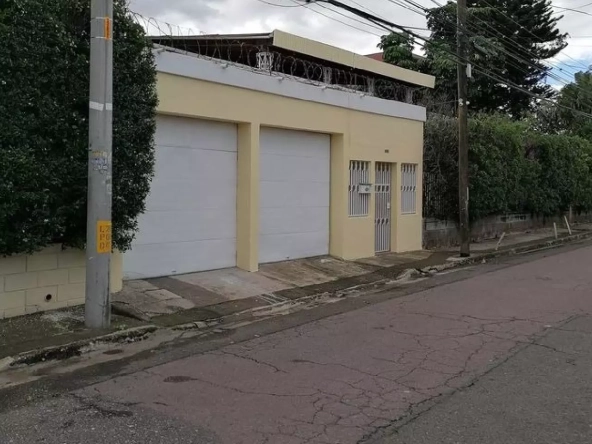 Fachada de la casa para oficina en Col. Humuya, de 2 niveles de color amarillo.